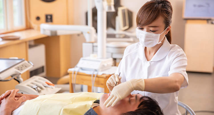 歯科医院でスタッフにお口の中をチェックされる男性