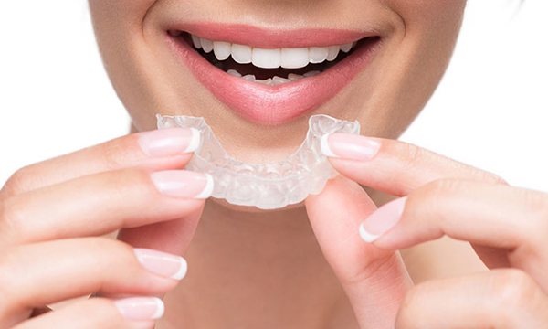 透明なマウスピースを口元に近づけている様子