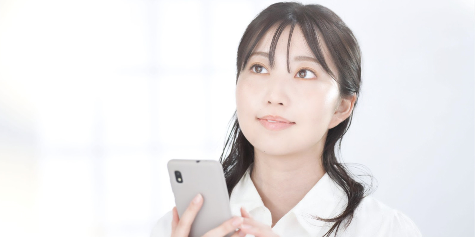 スマートフォンを片手に考える女性