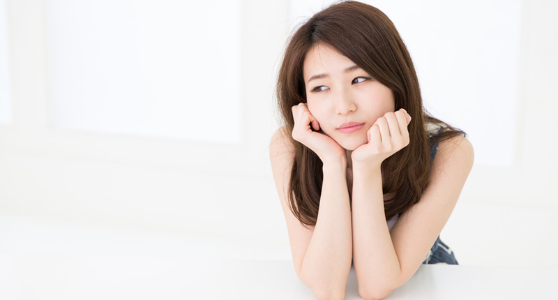 両手で頬杖をつき、悩む女性