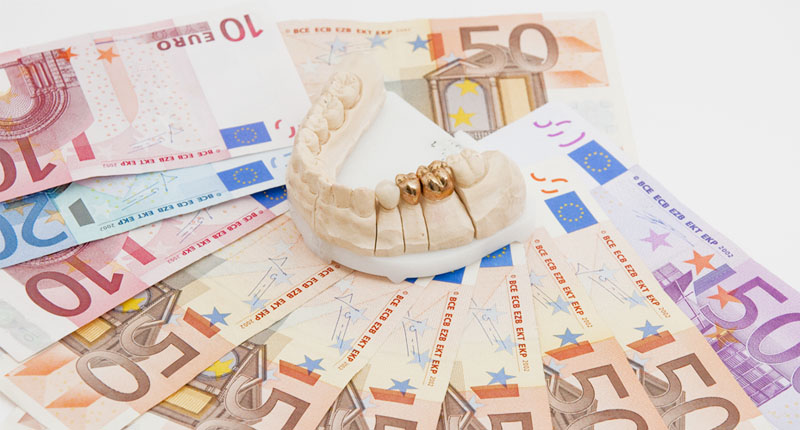 お金の上に模型についているセラミックの白いクラウン1本と金色のクラウン2本