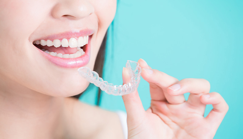 透明なマウスピースを口元に近づけている様子