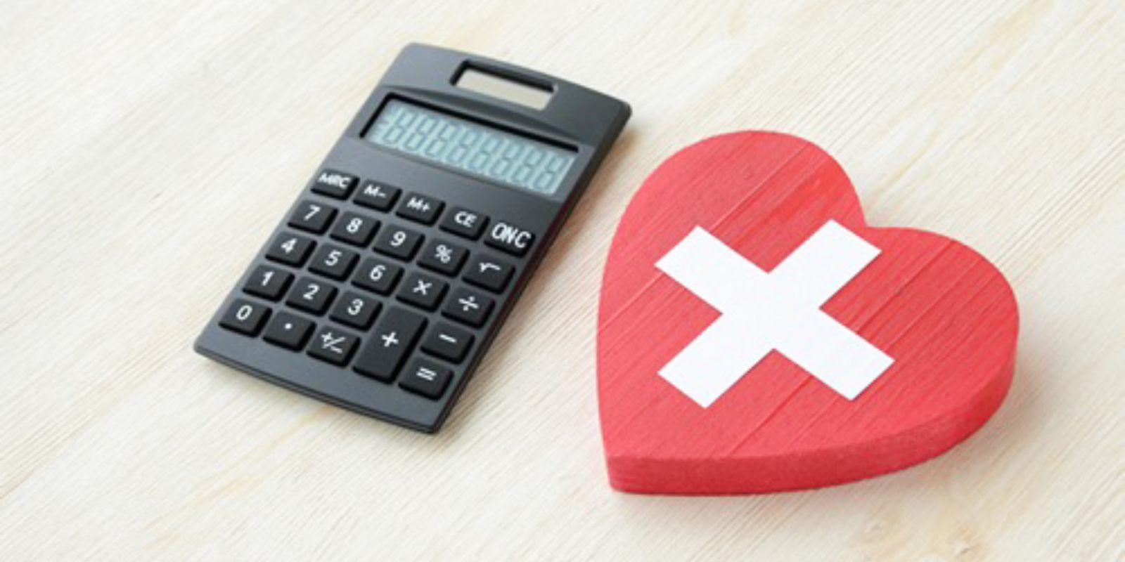 電卓と赤いハートに十字マークの書かれた物の写真