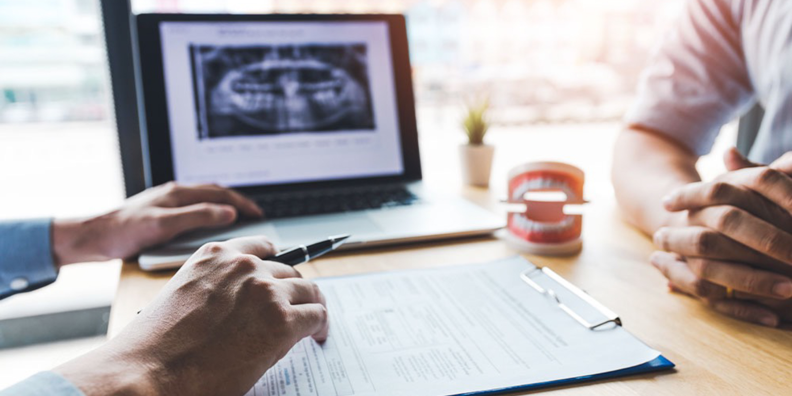 モニターや模型を使い患者さまに説明する歯科医師