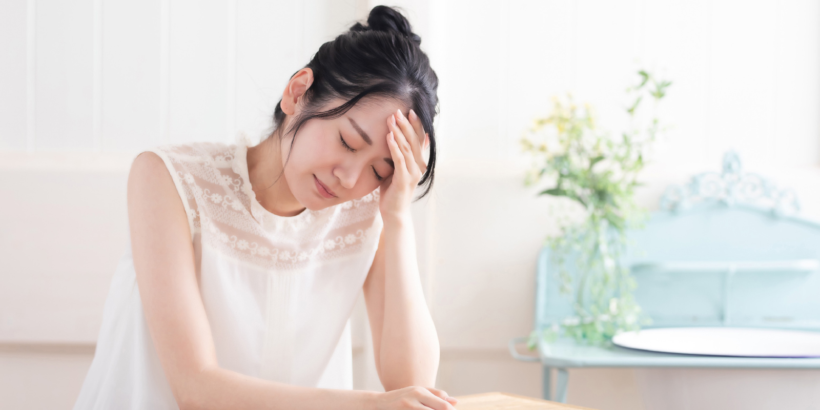 頭に手を当て考える女性