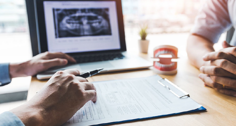 モニターや模型を使い患者さまに説明する歯科医師