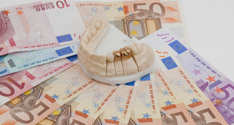 お金の上に模型についているセラミックの白いクラウン1本と金色のクラウン2本