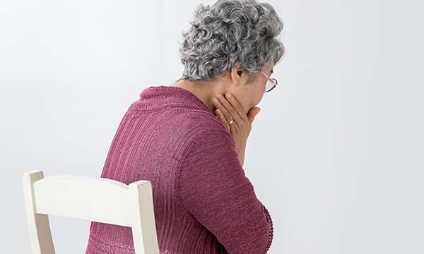 頬に手を当て痛がる老人の後ろ姿