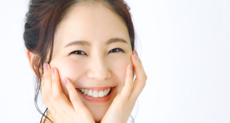 頬に手を添え歯を見せて微笑む女性の写真