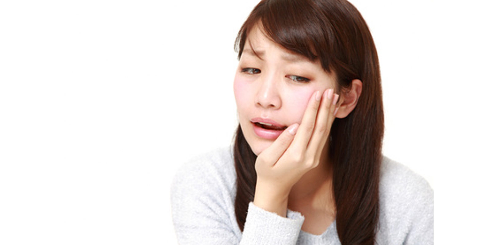 痛みで顎を手でおさえる女性