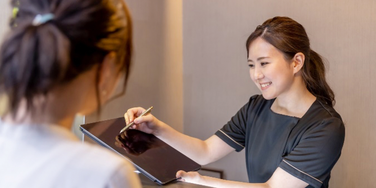 タブレットを用いて説明する笑顔のスタッフ