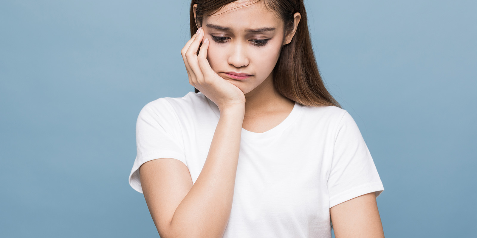 顎に手を当て、悲しそうな表情をする女性