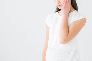 頬をおさえる女性