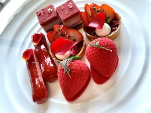 赤いイチゴや花びら等が乗った4種類の小さなケーキの写真